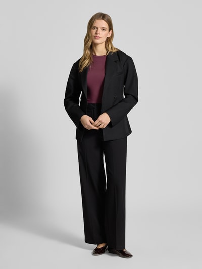 Frauenmodel trägt schwarze Bundfaltenhose mit Viskose-Anteil Modell 'ROSA' von Pieces, Wide Leg, High Waist, Ganzkörperansicht von vorne.