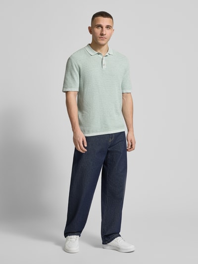 Männermodel trägt Regular Fit Poloshirt mit Strukturmuster Modell 'GEORGE' von Jack & Jones aus Baumwoll-Mix, Knopfleiste, Ganzkörperansicht von vorne.