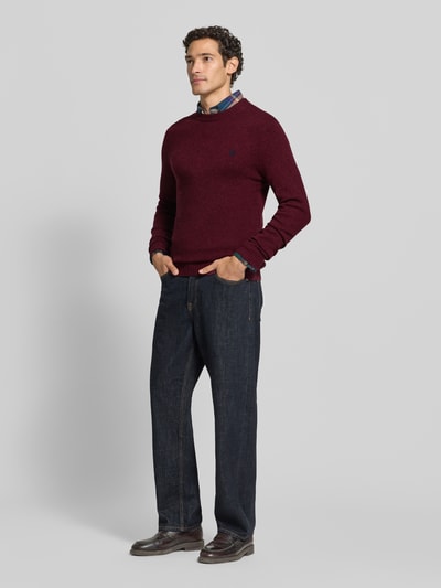 Männermodel trägt Slim Fit Strickpullover aus reiner Wolle mit Label-Stitching von MCNEAL in Bordeaux, gerade Formen, glatte Textur, gerippte Abschlüsse, Ganzkörperansicht von vorne