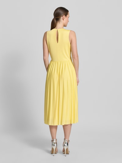 Frauenmodel trägt Abendkleid mit V-Ausschnitt Modell 'Amanda' von GUIDO MARIA KRETSCHMER WOMAN aus gelbem Satin, taillierter Schnitt, Midikleid, Rückansicht ganzkörper.