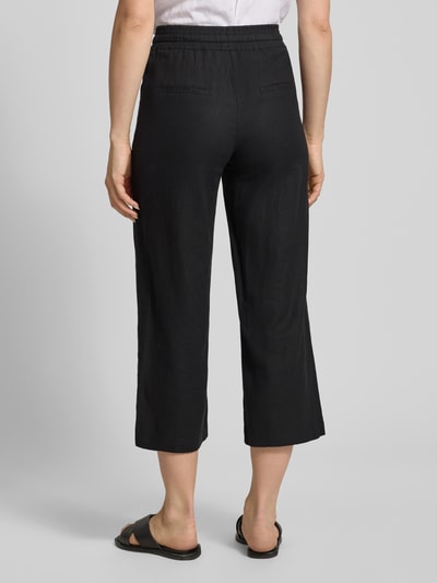 Frauenmodel trägt Wide Fit Stoffhose aus Leinen-Mix mit Viskose-Anteil Modell 'Ina' von Soyaconcept, Damen, elastischer Bund mit Tunnelzug, verkürzte Passform, schwarze Farbe, glatte Textur, Ganzkörperansicht Rückansicht.