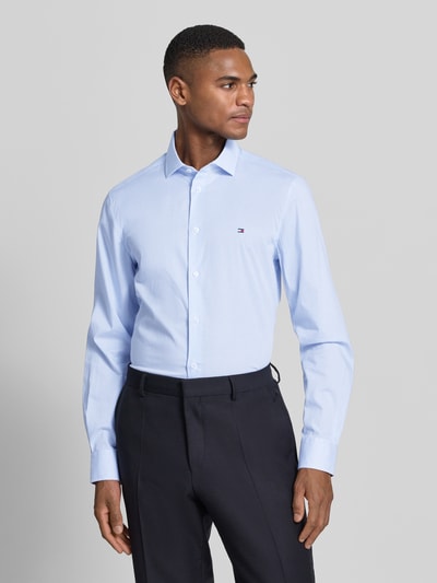 Męski model nosi Slim Fit Freizeithemd aus Baumwoll-Mix von Tommy Hilfiger Tailored, jasnoniebieska krata, długi rękaw, bawełniany stretch, logo, widok całej sylwetki z przodu.
