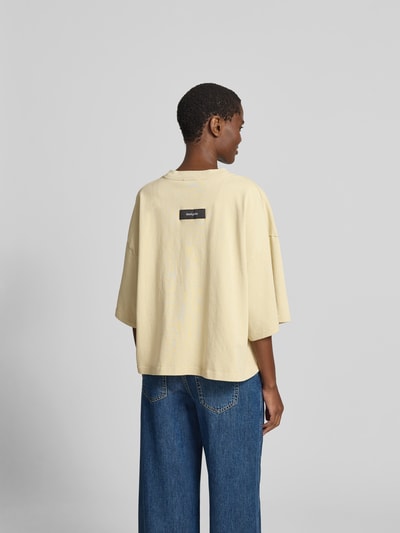 Frauenmodel trägt T-Shirt mit Rundhalsausschnitt von black palms in Beige, reine Baumwolle, relaxed Fit, Ganzkörperansicht Rückansicht.