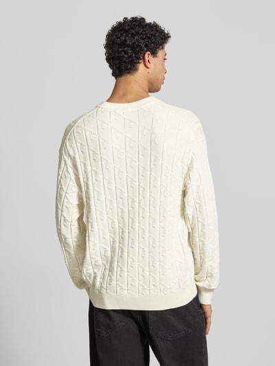 Männermodel trägt Strickpullover mit Rundhalsausschnitt Modell 'EASY' von Calvin Klein Jeans, cremefarben, Baumwolle, Ganzkörperansicht Rückansicht.