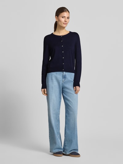 Frauenmodel trägt Regular Fit Cardigan aus Viskose-Mix von Christian Berg Woman in Dunkelblau mit Rundhalsausschnitt, Knopfleiste, kombinierbar zu hellblauer Jeans, Ganzkörperansicht von vorne.