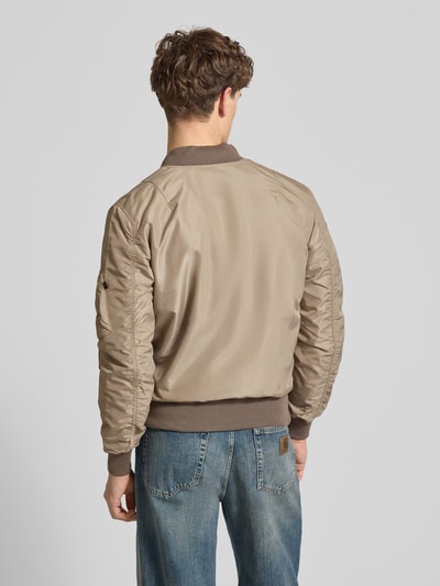 Männermodel trägt Regular Fit Bomberjacke mit Logo-Patch von Alpha Industries, beige mit Rippbündchen, Rückenansicht, Ganzkörperansicht Rückansicht.