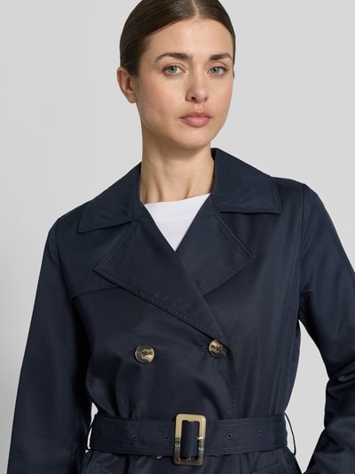 Frauenmodel trägt Trenchcoat mit Gürtel und seitlichen Eingrifftaschen von Zero in Dunkelblau, Reverskragen, Nahaufnahme Oberkörper, Taillierter Schnitt, Doppelreihige Knopfleiste, Gürtel mit Dornschließe, Rückenlänge 100 cm, Schulterbreite 37 cm, Brustweite 50 cm, Ärmellänge 59 cm.
