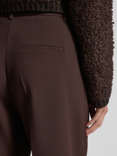 Vrouwenmodel draagt Stoffhose mit Bundfalten van Smith and Soul, bruin, losse pasvorm, achterzakken, detailopname achterkant.