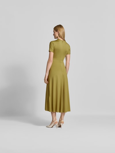 Frauenmodel trägt Midikleid mit Raffungen von Victoria Beckham in Gelbgrün, elastischer Material-Mix, tailliert, Rückansicht Ganzkörperansicht.