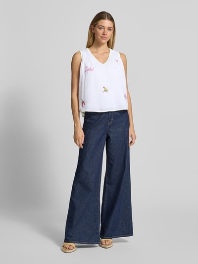 Frauenmodel trägt Blusentop mit Stitchings von Marc Cain aus reiner Baumwolle, weiß, Regular Fit, V-Ausschnitt, Ganzkörperansicht von vorne.