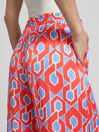 Frauenmodel trägt Stoffhose aus reiner Viskose von Milano Italy mit weitem Bein und elastischem Bund im grafischen Muster, Nahaufnahme Rückansicht.