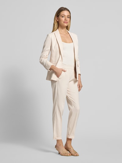 Frauenmodel trägt Straight Fit Leinenhose mit Viskose-Anteil von Marc Cain, Damen Leinenhose im Elastischer Leinen-Mix mit Viskose-Anteil, elastischer Bund, Gesäßtaschen, Bundweite 38 cm, Innenbeinlänge 67 cm, helles Beige, glatte Textur, Ganzkörperansicht von vorne.
