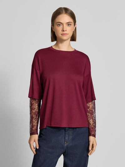 Frauenmodel trägt Regular Fit Langarmshirt mit Viskose-Anteil Modell 'TAHLIA' von ONLY in Dunkelrot mit Spitzenärmeln, Damen Langarmshirt von ONLY, Ganzkörperansicht von vorne.