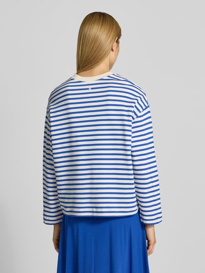 Männermodel trägt oversize’ową bluzę z czystej bawełny model 'FRANKA MAARLEN' od Armedangels, dwukolorowy wzór w paski, wyhaftowane logo, okrągły dekolt, długi rękaw, dzianina dresowa, widok całej sylwetki z tyłu.