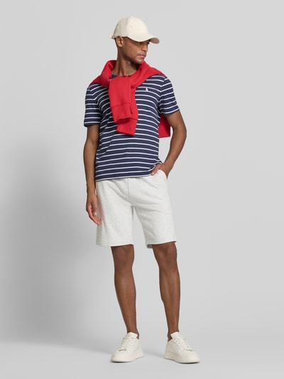 Männermodel trägt Relaxed Fit Sweatshorts aus Baumwoll-Mix von Tommy Hilfiger in Melange-Optik, Label-Stitching-Applikation, Ganzkörperansicht von vorne.