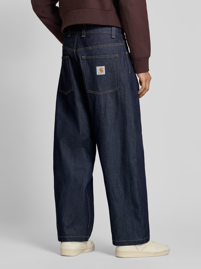 Männermodel trägt Relaxed Fit Jeans mit Eingrifftaschen Modell 'Brandon' von Carhartt Work In Progress, Material-Mix, dunkles Blau, Ganzkörperansicht Rückansicht.