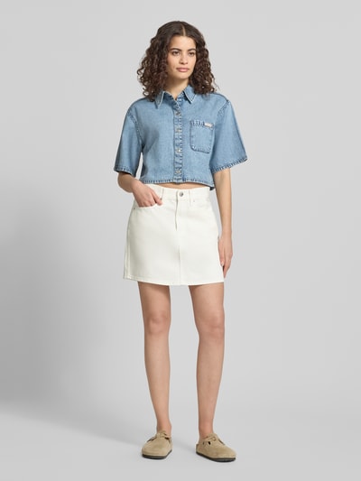 Vrouwenmodel draagt jeansrok im 5-pocketdesign model '90S' van Calvin Klein Jeans in materiaalmix met katoen, straight fit, mini-jurk, labeldetail, knoop- en ritssluiting, bandwijdte en totale lengte maat 27 beide 40 cm, geheel voorkantaanzicht