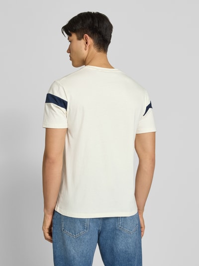 Männermodel trägt Regular Fit T-Shirt mit Logo-Detail Modell 'Caserio' von Ellesse, weiß mit dunkelblauen Akzenten, Jeans, Ganzkörperansicht Rückansicht.