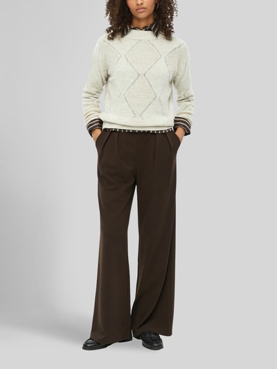 Modelka kobieca nosi Pullover mit leichtem Stehkragen od S. OLIVER BLACK LABEL, jasny beż z wzorem argyle, dzianina z mieszanki wełny i alpaki, długie rękawy zakończone ściągaczem, proste faktury, widok całej sylwetki z przodu.