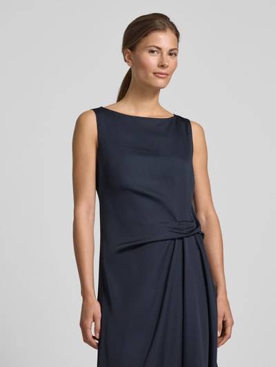 Frauenmodel trägt Cocktailkleid mit asymmetrischem Saum von Vera Mont in Dunkelblau, U-Boot-Ausschnitt, Raffung an der Taille, Nahaufnahme Oberkörper.