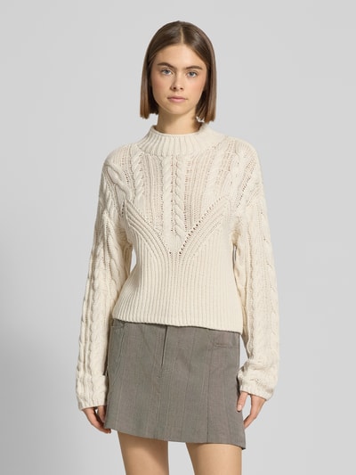 Frauenmodel trägt Slim Fit Pullover in Strick-Optik Modell 'Haysa' von Noisy May aus Baumwoll-Mix, mit Rundhalsausschnitt, eingefasste Ärmelabschlüsse, Rückenlänge 58 cm, Ärmellänge 67 cm, cremefarbene Struktur, Ganzkörperansicht von vorne.