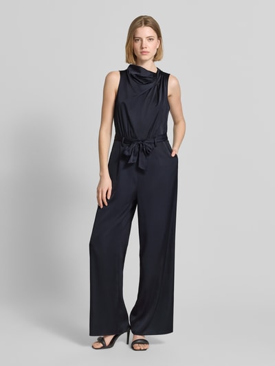 Frauenmodel trägt Jumpsuit aus Satin im ärmellosen Design von comma in Schwarz mit Stoffband, taillierter Passform, Ganzkörperansicht von vorne.