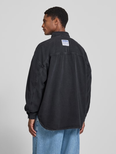 Männermodel trägt Relaxed Fit Jeanshemd mit Kentkragen Modell 'JAZY' von American Vintage in Schwarz, Reine Baumwolle, Rückenlänge 81 cm, Schulterbreite 67 cm, Ärmellänge 58 cm, Ganzkörperansicht Rückansicht.