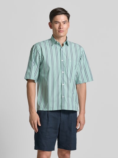 Männermodel trägt Regular Fit Freizeithemd mit Kentkragen und Brusttasche von Lindbergh in Grün mit Streifenmuster, Ganzkörperansicht von vorne. Reine Baumwolle, Allover-Look, kurze Ärmel, Label-Stitching.