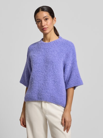 Modelka nosi Strickpullover mit gerippten Abschlüssen Modell 'ZOLLY' od American Vintage, fioletowy melanż, luźny krój, widok całej sylwetki z przodu.