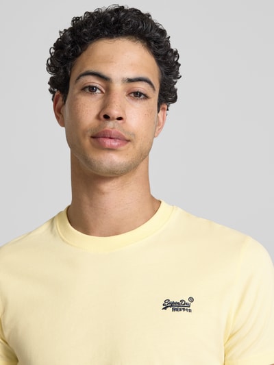 Männermodel trägt Regular Fit T-Shirt mit Logo-Stitching von Superdry in Gelb aus Reine Baumwolle, Rundhalsausschnitt, Nahaufnahme Oberkörper.
