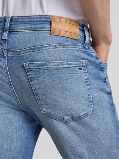 Mężczyzna nosi Slim Fit Jeans aus Baumwoll-Mix Modell 'AUSTIN' od Tommy Jeans, jasnoniebieski denim, twill, label patch, logo-stitching, detal kieszeni, detal paska, perspektywa: zbliżenie na tył.