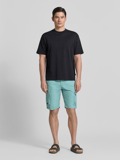 Männermodel trägt Bermudas mit Cargotaschen von camel active in lichtblauw, reine katoen, regular fit, met steekzakken en cargozakken, label-detail, volledige voorkantaanzicht.