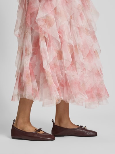 Vrouwenmodel draagt A-lijn maxi-rok met ruchesmodel 'SKY' van Only, roze bloemenprint, tule, elastische tailleband, detailopname benen.