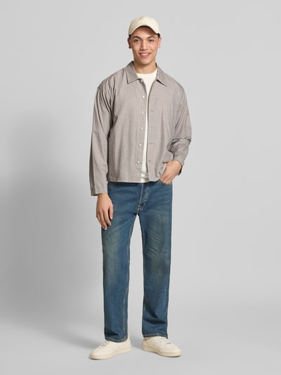 Mannelijk model draagt Regular Fit Freizeithemd aus Baumwolle Modell 'AUSTIN' van Jack & Jones, geruite stof in beige en bruin, knoopsluiting, borstzak, kentkraag, gecombineerd met blauwe jeans en witte sneakers, rechte vormen en gladde textuur, geheel vooraanzicht, context: herenoverhemd, pure katoen, regular fit, ruglengte 60 cm, schouderbreedte 45 cm, mouwlengte 57 cm.