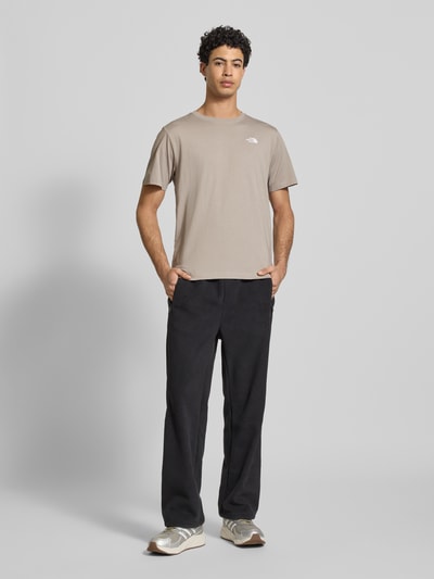 Männermodel trägt Regular Fit T-Shirt aus Baumwoll-Mix Modell 'EVOLUTION' von The North Face in Beige, Label-Detail, Ganzkörperansicht von vorne.