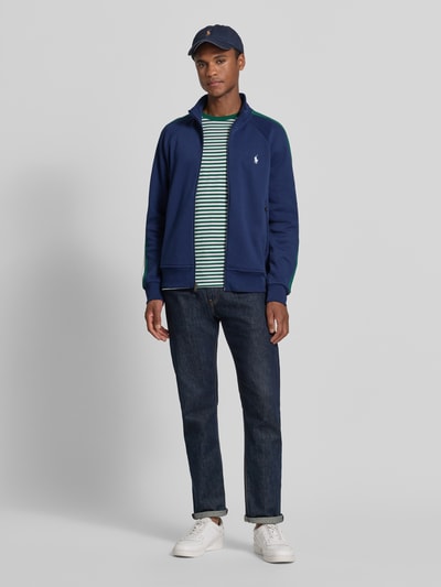 Männermodel trägt Regular Fit Sweatjacke aus Baumwoll-Mix von Polo Ralph Lauren in Dunkelblau, kombiniert mit Basic-Outfit, Ganzkörperansicht von vorne.
