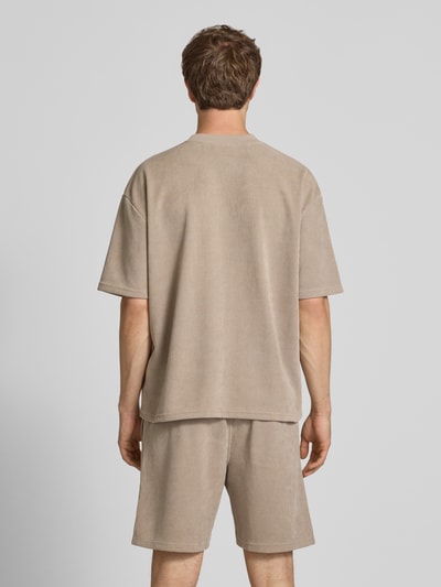 Männermodel trägt Oversized T-Shirt mit Logo-Stitching Modell 'Lagos' von Pegador aus Elastischer-Material-Mix in Beige, Oversized-Fit, Rückenlänge 65 cm bei Größe M, Ganzkörperansicht Rückansicht.