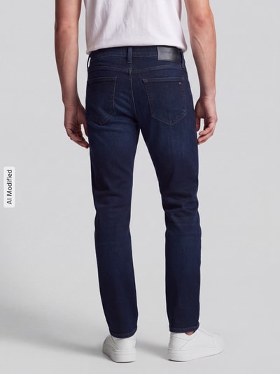 Männermodel trägt dunkelblaue Straight Fit Jeans aus Baumwoll-Mix Modell 'DENTON SLIM' von Tommy Hilfiger, Herren Straight Fit Jeans, Ganzkörperansicht Rückansicht, KI-modifiziertes Bild.