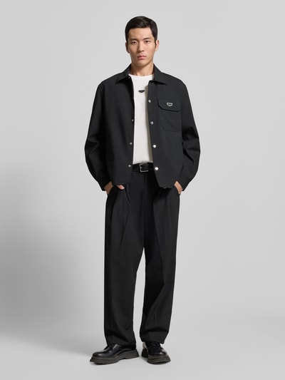 Männermodel trägt Hemdjacke mit Label-Detail von Antony Morato, schwarz, lockerer Schnitt, Kentkragen, Ganzkörperansicht von vorne