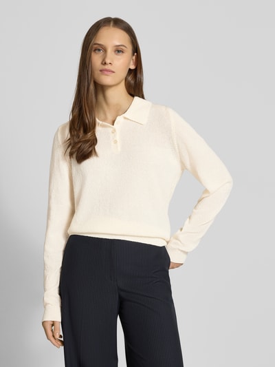 Frauenmodel trägt Langärmliger Polo-Strickpullover aus Bouclé-Garn von Review in Creme, lockere Passform, Strick-Optik, Polokragen, elastische Abschlüsse, Rückenlänge 55 cm, Ärmellänge 65 cm, Nahaufnahme Oberkörper.