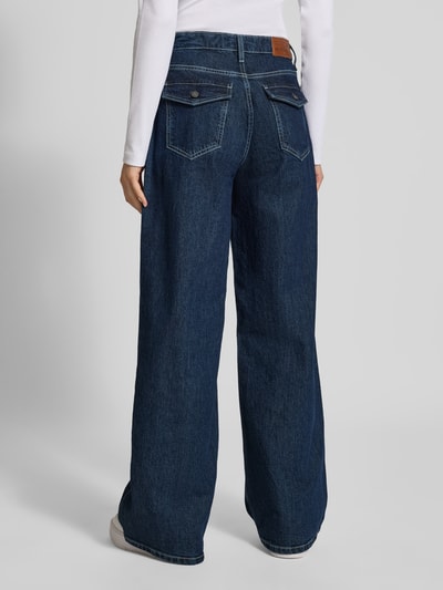 Frauenmodel trägt Wide Fit Jeans mit Logo-Patch von GUESS in Dunkelblau, 5-Pocket-Design, lockere Form, Ganzkörperansicht Rückansicht.