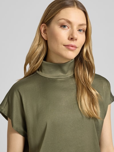 Kobiece modelka nosi Blusenshirt mit Stehkragen Modell 'ALARIA' von Drykorn, mieszanka materiałów z dodatkiem streczu, krój regular fit, długość tyłu w rozmiarze 36: 59 cm, kolor oliwkowy, delikatna tekstura, półmat, zbliżenie na górną część ciała.