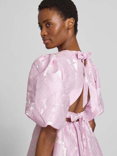 Frauenmodel trägt Cocktailkleid mit Puffärmeln Modell 'NOEALLA' von YAS, florales Muster in Hellrosa, Detailaufnahme Rückenansicht. A-Linie, Minikleid, Rundhalsausschnitt, Rückenlänge 85 cm, Brustweite 38 cm, Ärmellänge 35 cm.