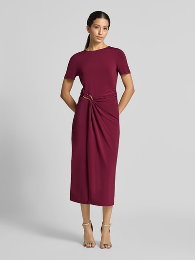 Frauenmodel trägt Midikleid mit Zierschnalle Modell 'Justine' von VILA in Weinrot, tailliert, Kurzarm, elastischer Mix, Ganzkörperansicht von vorne.