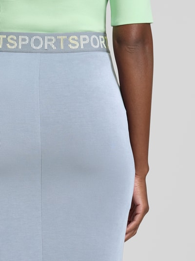 Frauenmodel trägt Midirock aus Lyocell-Mix von Marc Cain, hellblau, Statement-Print, elastischer Bund, Nahaufnahme Unterkörper.