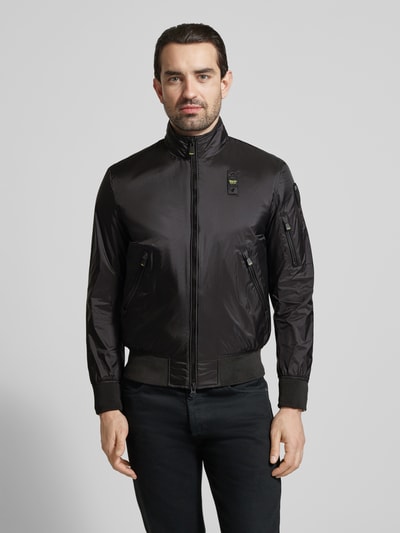 Männermodel trägt schwarze Jacke mit Reißverschlusstaschen Modell 'Brahms' von Blauer Usa, glatte Struktur, Ganzkörperansicht von vorne.