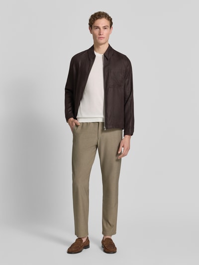 Męski model nosi spodnie Straight Leg Hose mit Viskose-Anteil Modell 'ROBERT' von SELECTED HOMME, z efektem melanżu, krój straight leg, naszywka z logo, elastyczny ściągacz z tunelem, wpuszczane kieszenie boczne, kieszenie z wypustkami, kolor beżowy, melanżowa faktura, ganzkörperansicht von vorne.