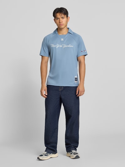 Męski model nosi koszulkę polo Relaxed Fit Poloshirt mit Logo-Stitching od Champion, jasnoniebieska, wyhaftowane logo, kołnierzyk polo, krótki rękaw, długość tyłu w rozmiarze M: 70 cm, Ganzkörperansicht von vorne.
