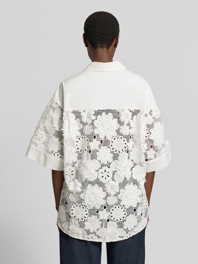 Frauenmodel trägt Relaxed Fit Kurzarmbluse aus reiner Baumwolle Modell 'KALI' von Essentiel Antwerp in Weiß, florale Lochstickerei, Ganzkörperansicht Rückansicht. Damen Kurzarmbluse von Essentiel Antwerp.