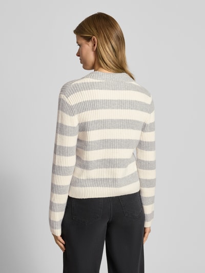 Frauenmodel trägt Strickjacke mit Streifenmuster und Polokragen von Review, Material-Mix mit Stretch-Anteil, Slim Fit, Rückenlänge 52 cm, Ärmellänge 65 cm, Kontrast aus hellen und grauen Tönen, weiche Rippstruktur, Ganzkörperansicht Rückansicht.